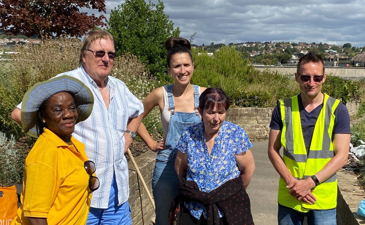 A group of volunteers photographed by the Sensory Garden in bright sunlight