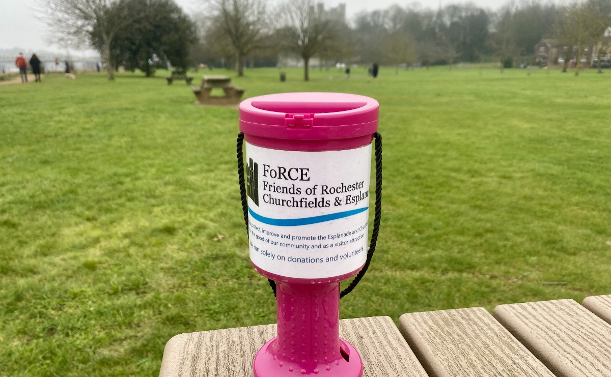 A FoRCE branded donation collecting box on a bench in Esplanade Gardens