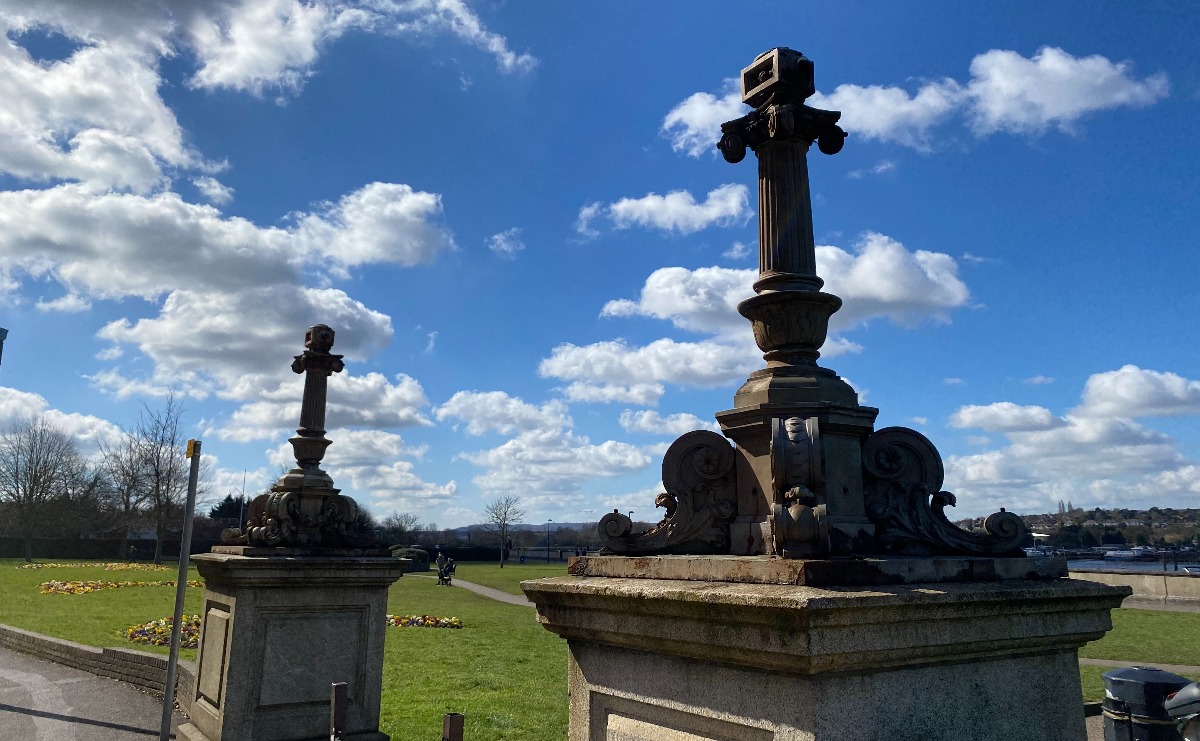 The ornate lights mounted on their granite plinths at the northern entrance to the Esplanade Gardens: the scrollwork bases and columns are present, but not the lantern section