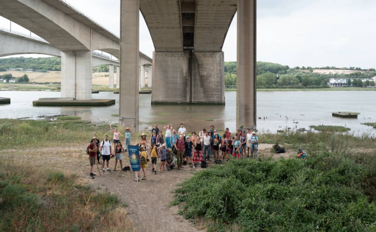 A group of about twenty people pose for a photo under one of the dramatic concrete spans of the Medway Viaduct