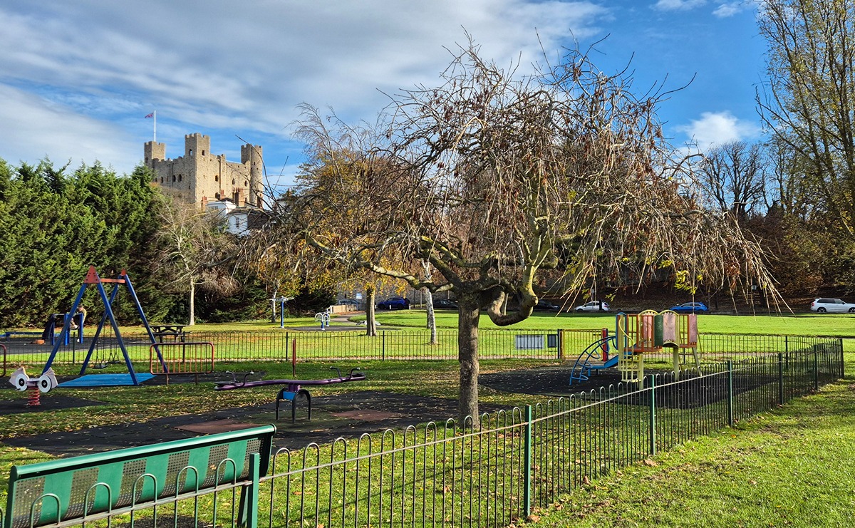 A view of the children's play area in Esplanade Gardens on a bright autumnal day, with Rochester Caslte in the backgorund