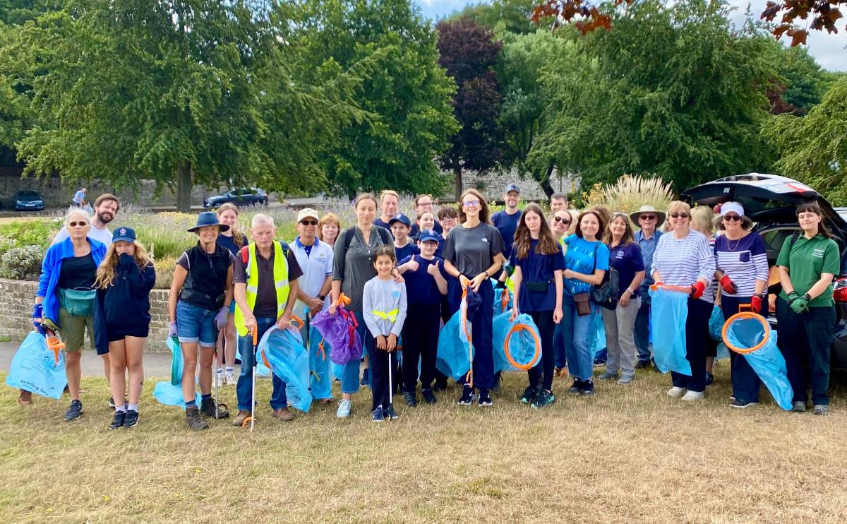 A group photo of our volunteers with Lauren Edwards MP, holding gardening tools, litter pickers and litter bag hoops