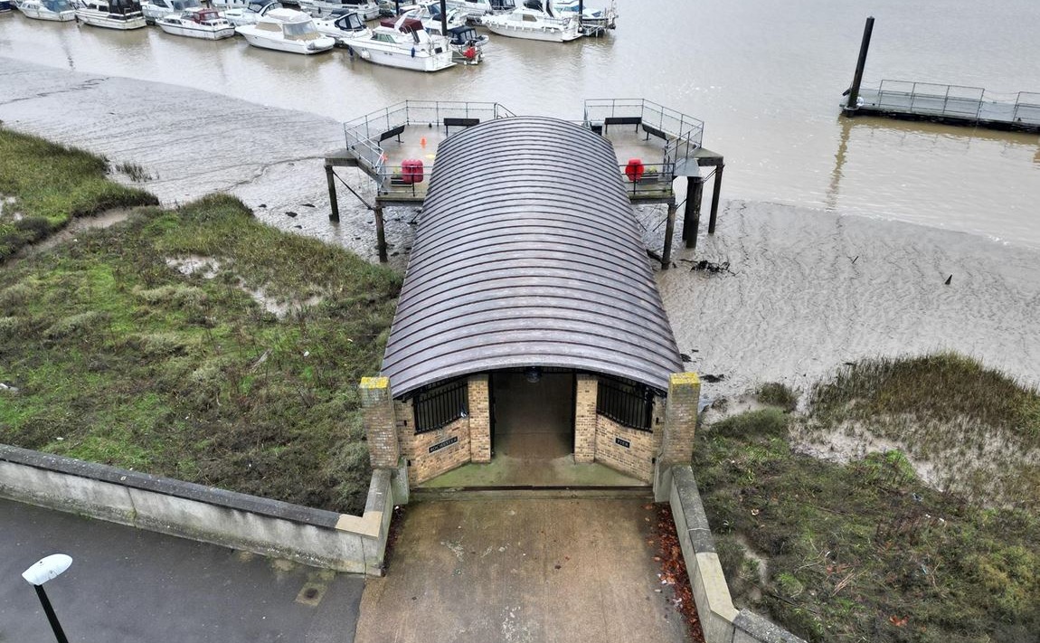 A view of Rochester Pier from above at low tide, showing the canopy and the surrounding saltmarsh and mud