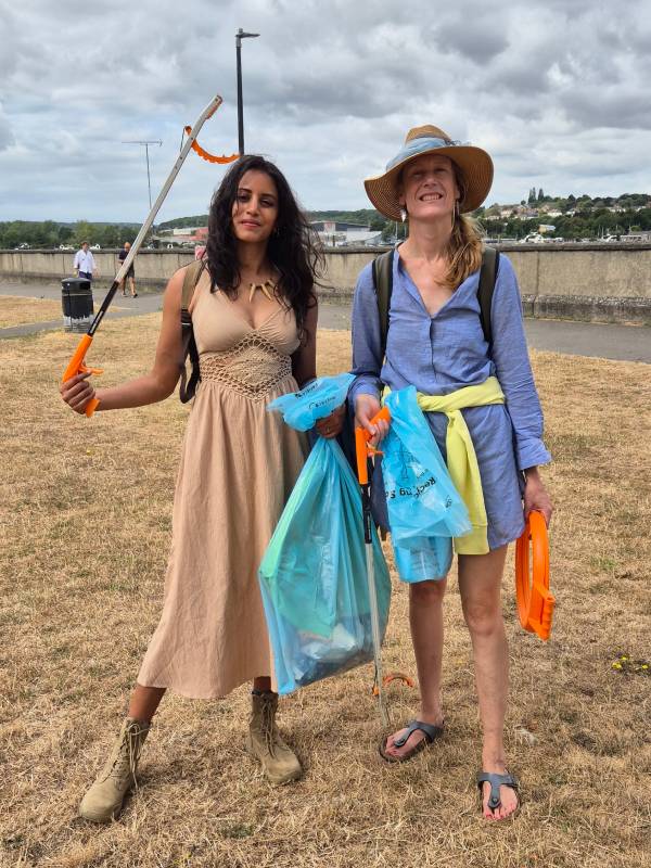 Two women pose with litter picker, bag hoop and bag