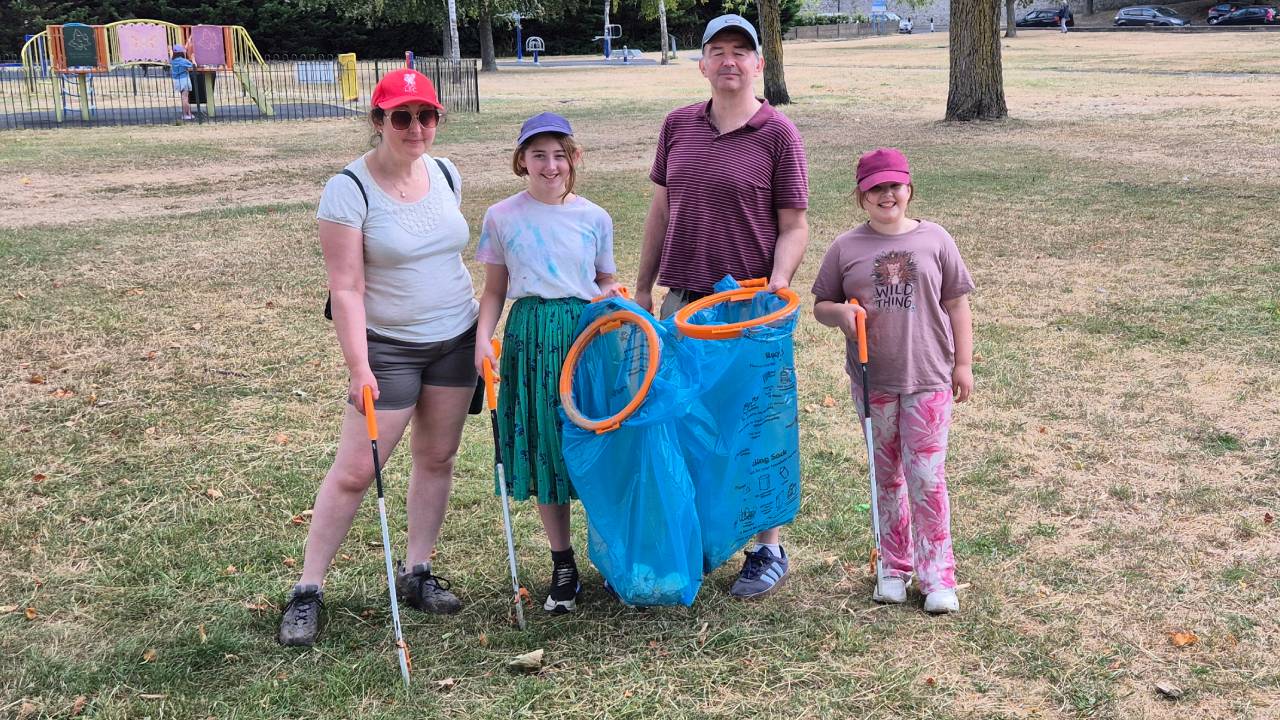 A family of four take a moment out of litter picking around Esplanade Gardens to pose for a photo