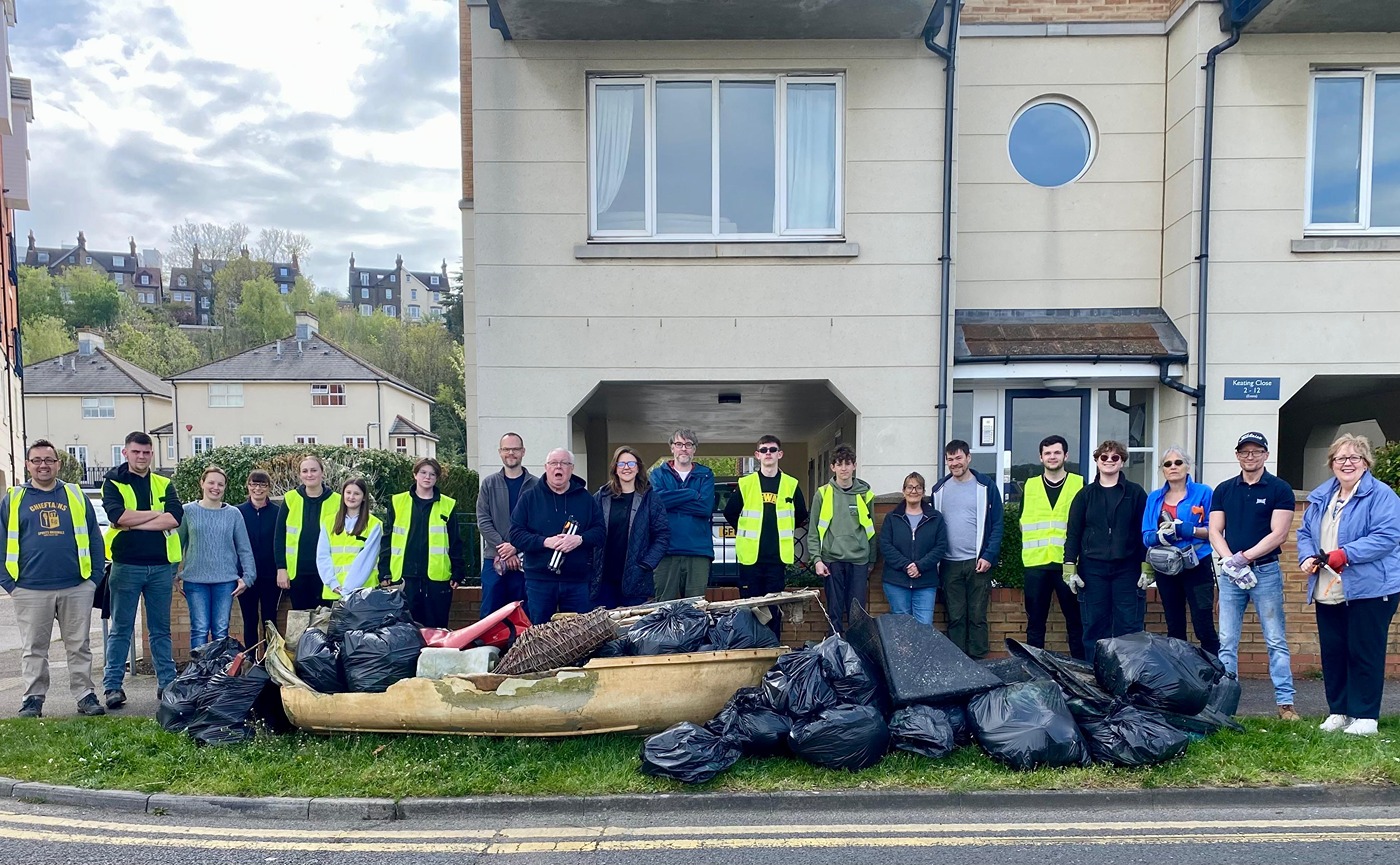 Volunteers pose for a group photo with many sacks of collected litter and some larger items, including an abandoned dinghy!
